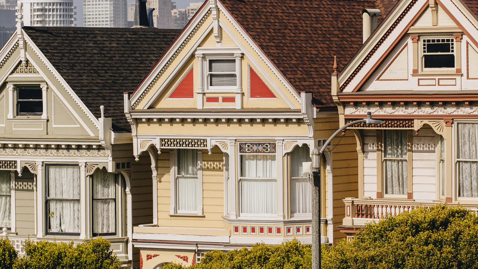 A connected row of Bay Area homes with the city skyline visible behind their rooflines.